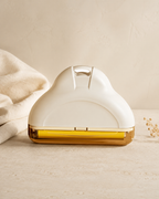 White and gold plastic Furvelis pet hair remover with a curved handle on a stone surface next to a beige fabric.